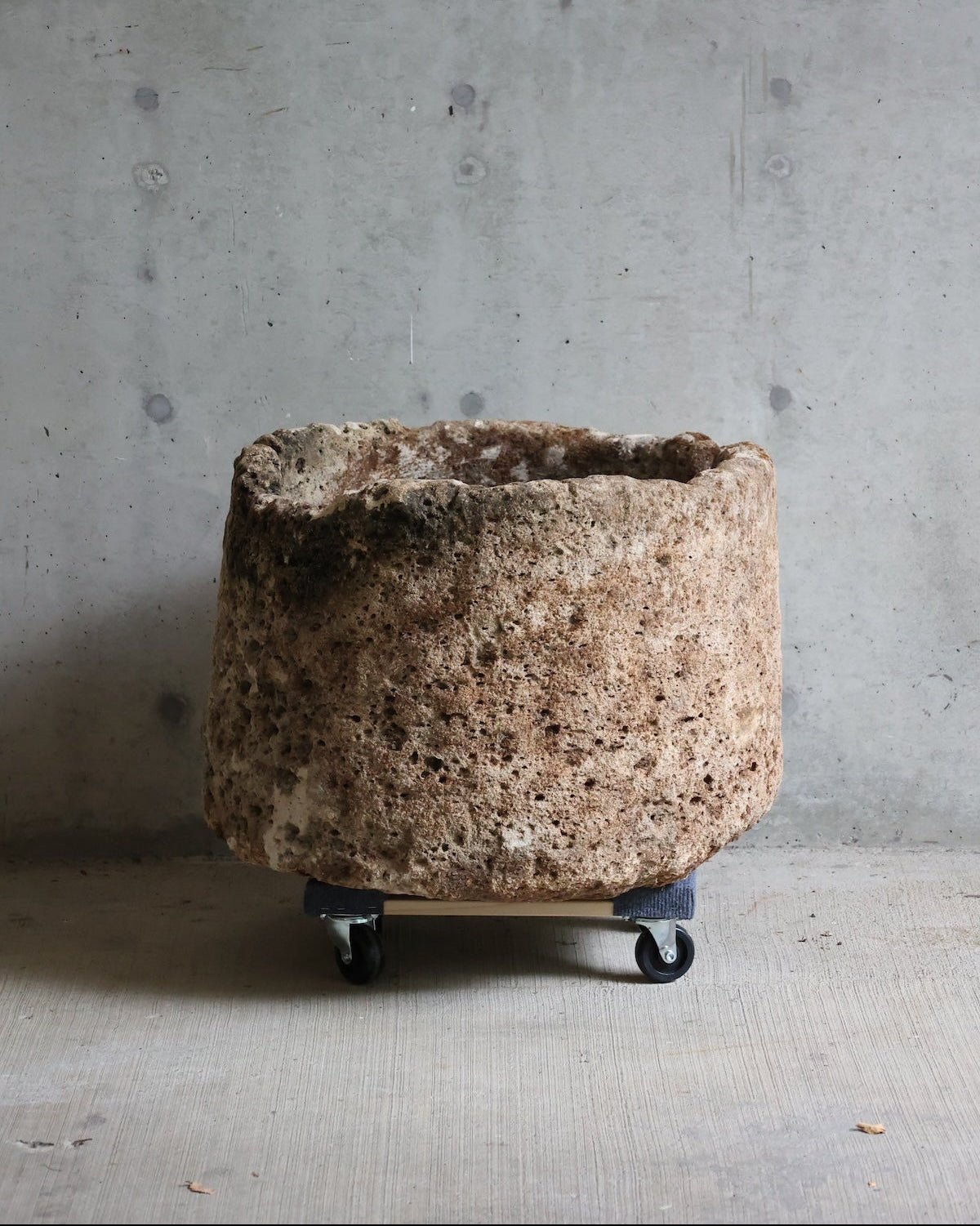 A large, rustic stone planter or decorative pot with a rough, porous texture